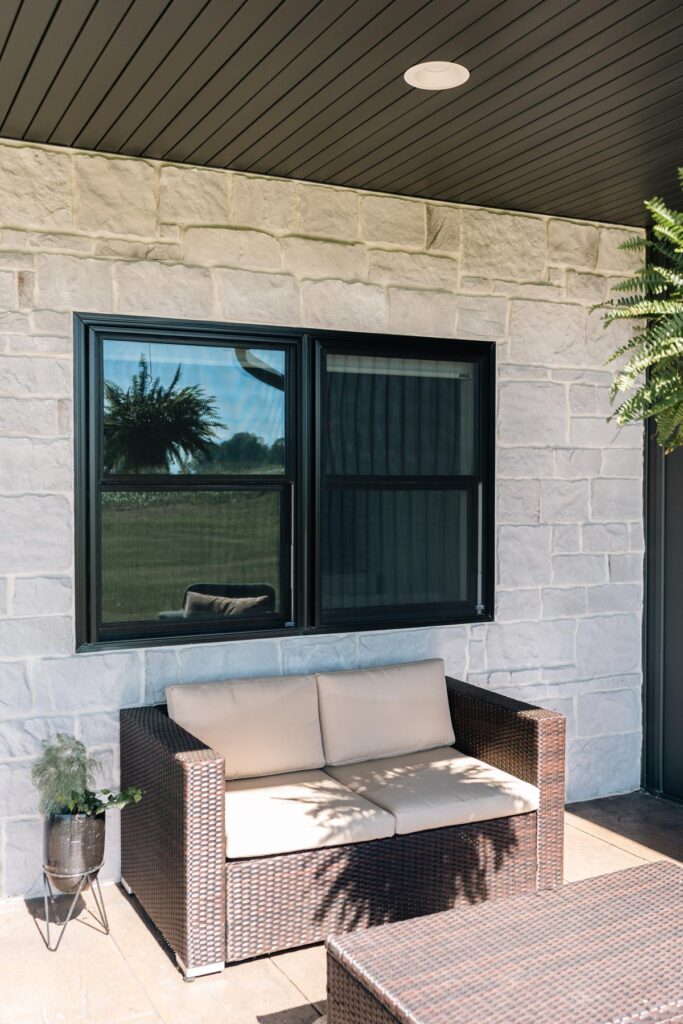 Outdoor patio with wicker couch and window.