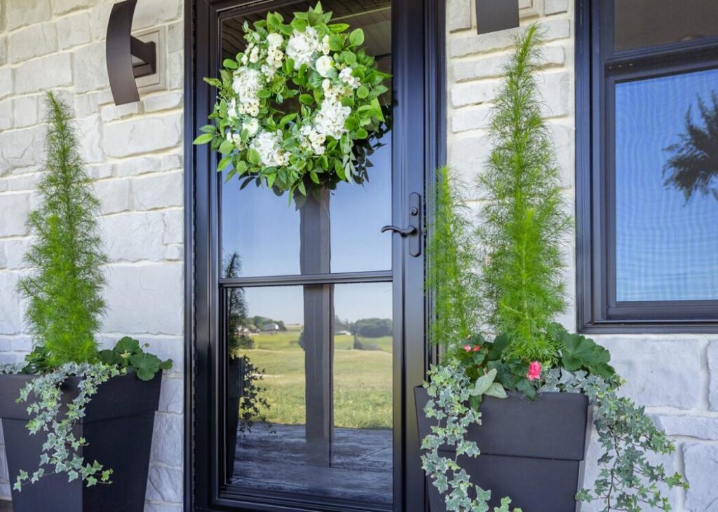 Front door with wreath and potted plants.