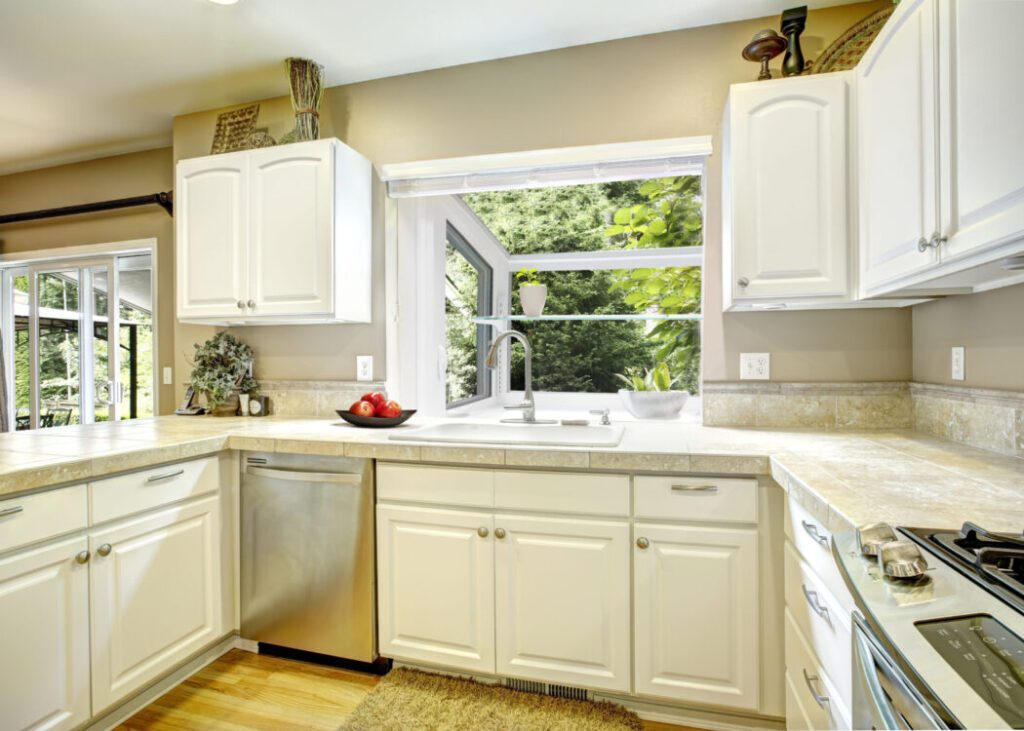 Bright kitchen with white cabinets and window.
